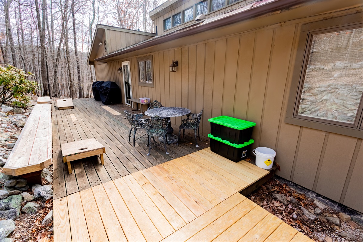 Back patio - view from the hot tub. 2 propane gas grills, cornhole boards, metal dining table and chairs, built-in benches. the front patio has 2 picnic tables.