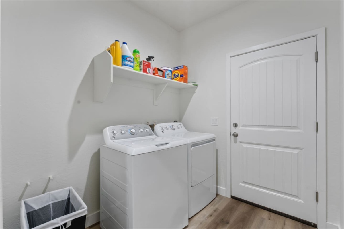 Convenient laundry setup with washer, dryer, supplies, and direct exterior door access.
