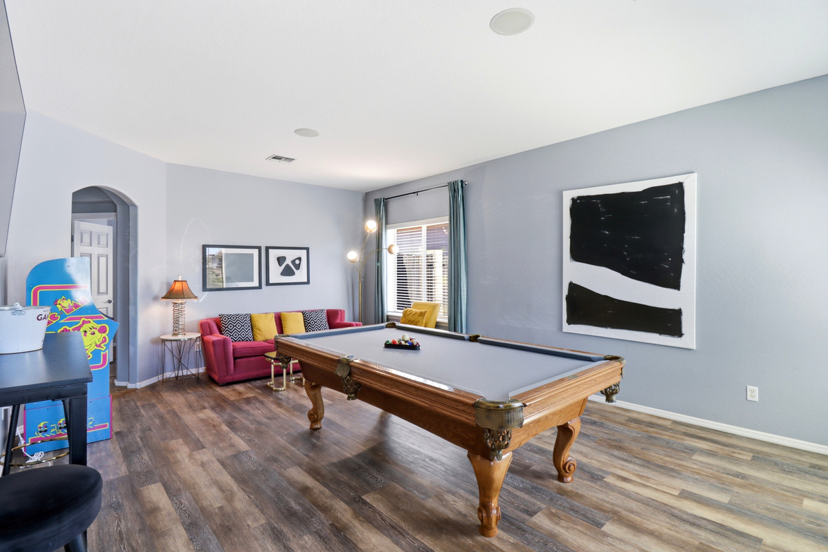 Game room with a pool table, arcade game, and seating for a fun night in.
