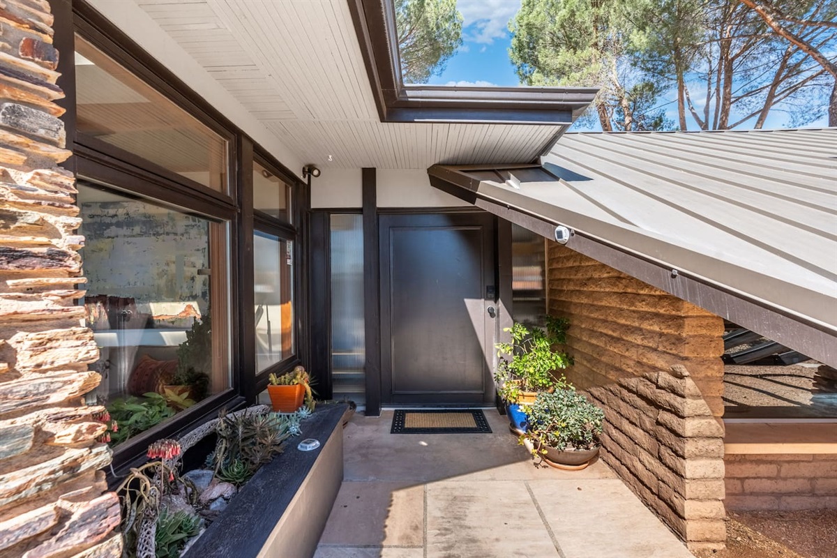 Inviting front entry with sleek modern door, skylight above, and thoughtfully styled planters.