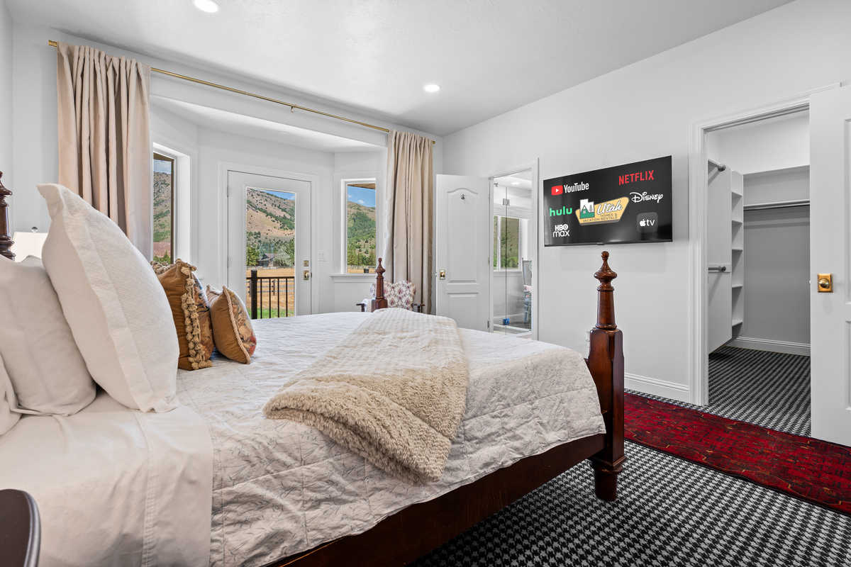 Unwind in the elegant primary suite with a wall-mounted smart television, generous closet space, and direct access to both the private bathroom and balcony.