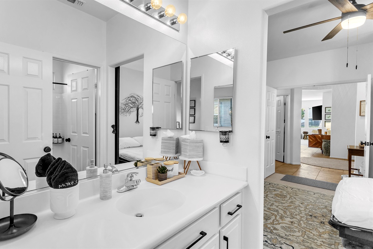 Bright dual-entry bathroom with elegant mirrors and modern black hardware connecting both guest rooms.”