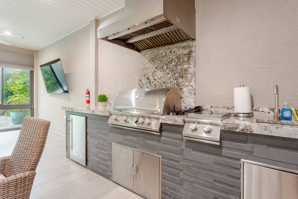 Luxurious sunroom featuring a beautifully appointed outdoor kitchen, generous entertaining space, and an elegant, open atmosphere—perfect for leisurely meals, sophisticated gatherings, and relaxed indoor-outdoor living.
