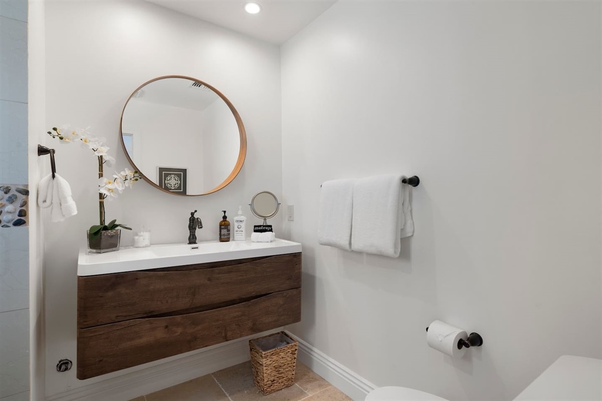 Step into relaxation! Our well-appointed bathroom offers everything you need, including a refreshing shower, chic round mirror, and elegant sink. Enjoy the perfect blend of style and function.