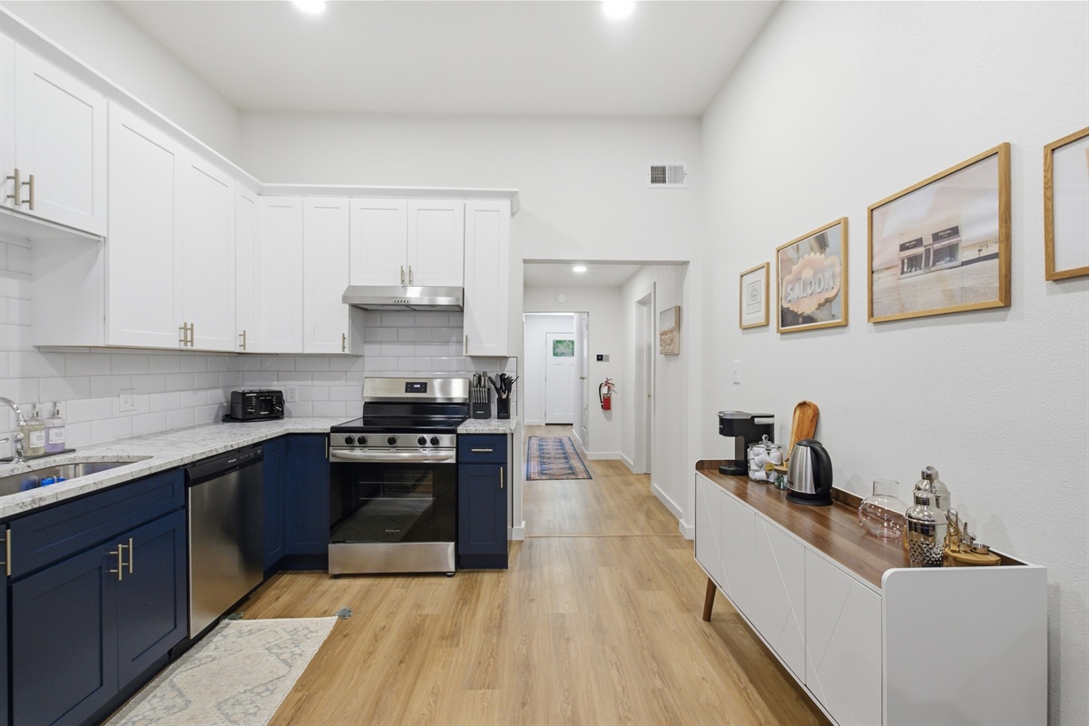 Full kitchen view from hallway showing navy island, Electric Stove, and Frigidaire Refrigerator. Premium appliance suite throughout.