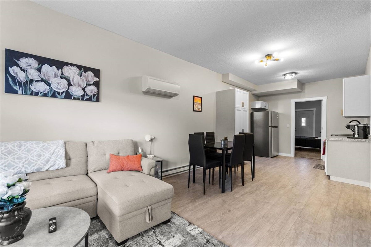 Open-concept living room with a sectional sleeper sofa, leading seamlessly into the dining area and modern kitchen for a spacious, connected feel.