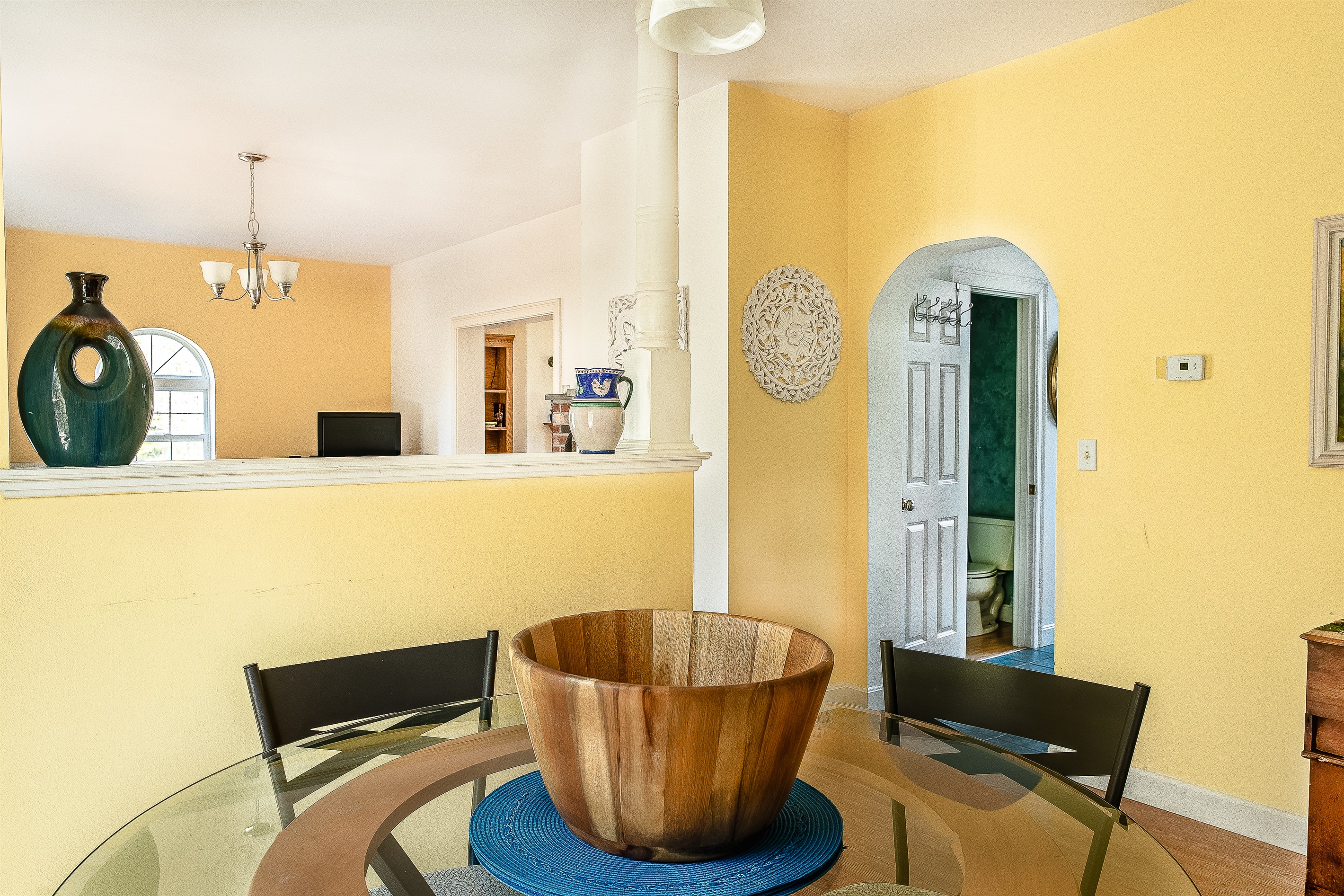 This view from the breakfast nook captures the clever layout of Seven Peaks Ridge. See the connection to the main living room and the convenient half-bath located through the arched hallway—ideal for group stays on the quiet side of Mount Desert Island.