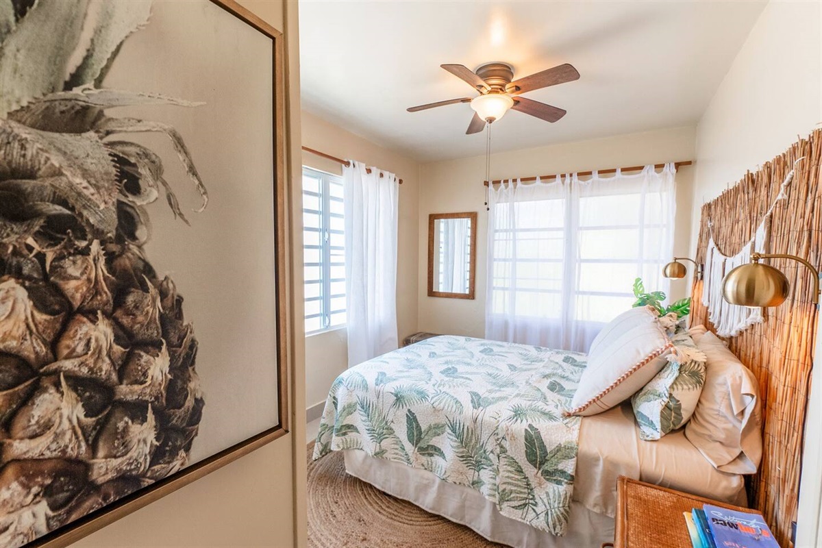 Large windows let in plenty of natural light in this queen bedroom. This bedroom is cooled by the Tradewinds and floor fan. 