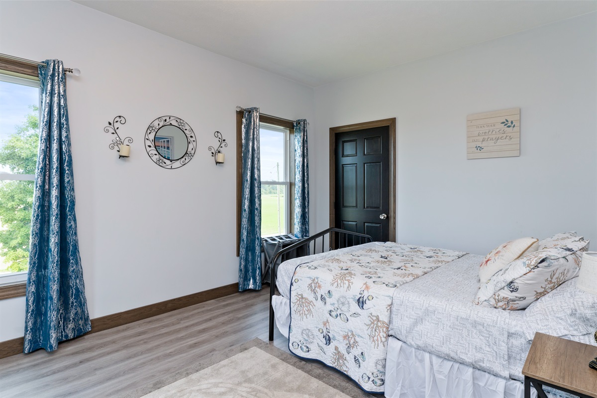 Spacious queen bedroom with large windows, elegant décor, and peaceful country views. Bedroom #3