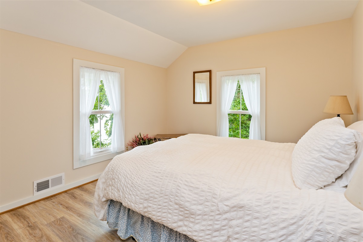 Inviting bedroom with serene views, soft natural light, and a plush white comforter for restful nights. Bedroom #1 queen