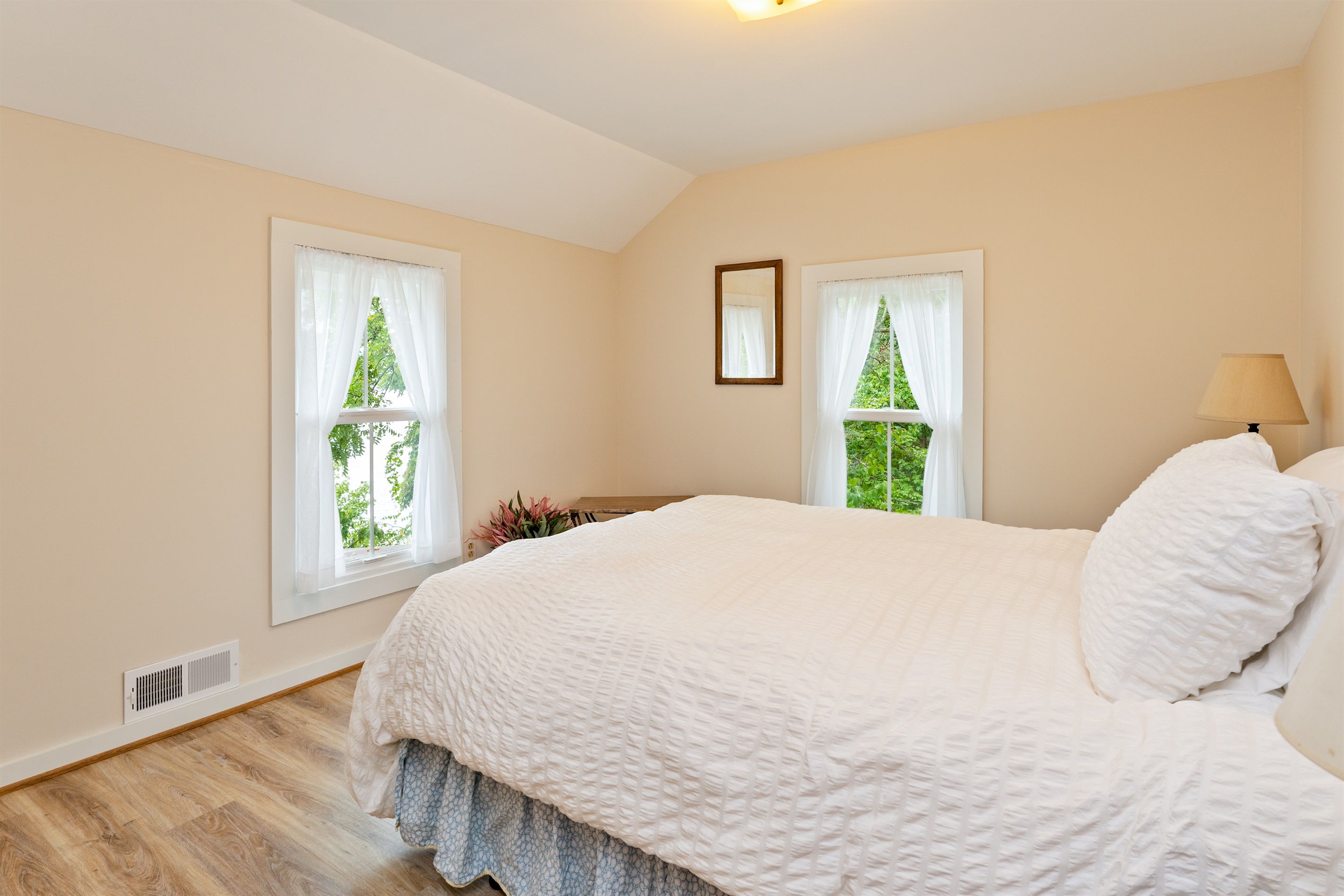 Inviting bedroom with serene views, soft natural light, and a plush white comforter for restful nights. Bedroom #1 queen