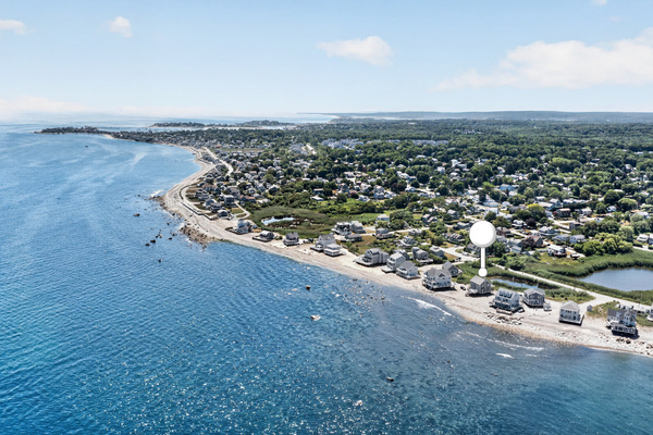 Aerial perspective highlights the sweeping coastline and the home’s prime location near the water.