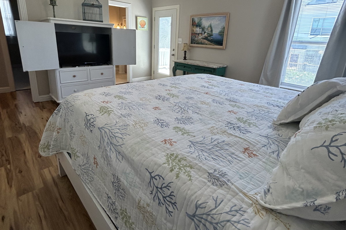 King Suite featuring an ensuite bath and balcony access with views of the lushly landscaped backyard oasis below. A twin rollaway bed is available to accommodate an additional guest, with ample space to position it comfortably at the foot of the bed.