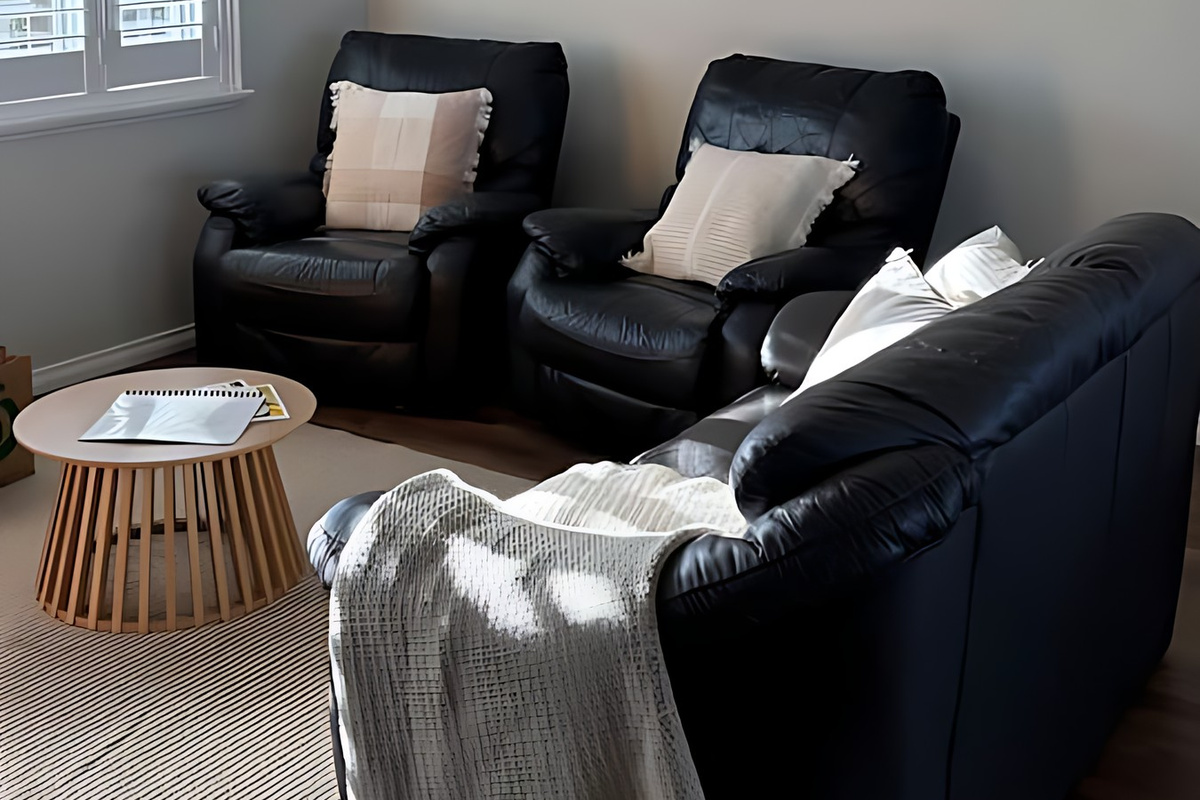 Another angle of the living room shows the two leather recliners and lounge beneath a raked white ceiling and black pendant light, with plantation shutters and a split-system air conditioner.