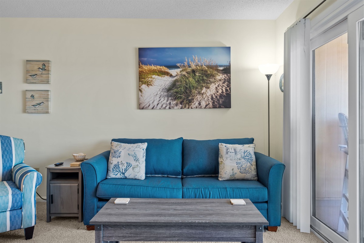 Coastal-inspired living area with plush seating, curated artwork, and direct access to the oceanview balcony