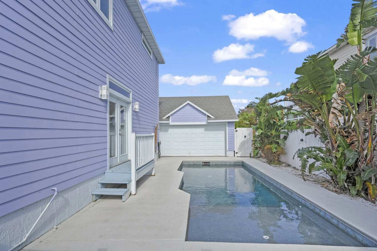 Pool, deck and the garage that became the tiki lounge, all in a single glance. Lift that door and the two spaces become one, which is exactly what you want on a long warm evening with a crowd of friends.