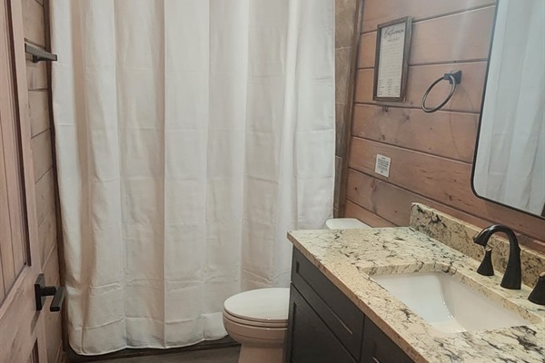 Single vanity bathroom with granite countertop and modern black fixtures.