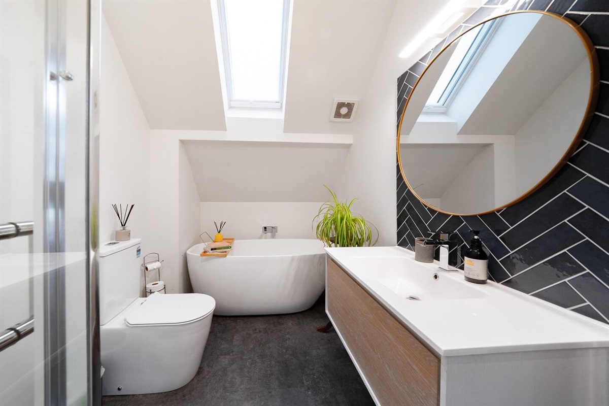 The upstairs bathroom includes a freestanding bath, vanity and toilet, giving Fernhill Mountain Escape a practical and comfortable upper-level setup.