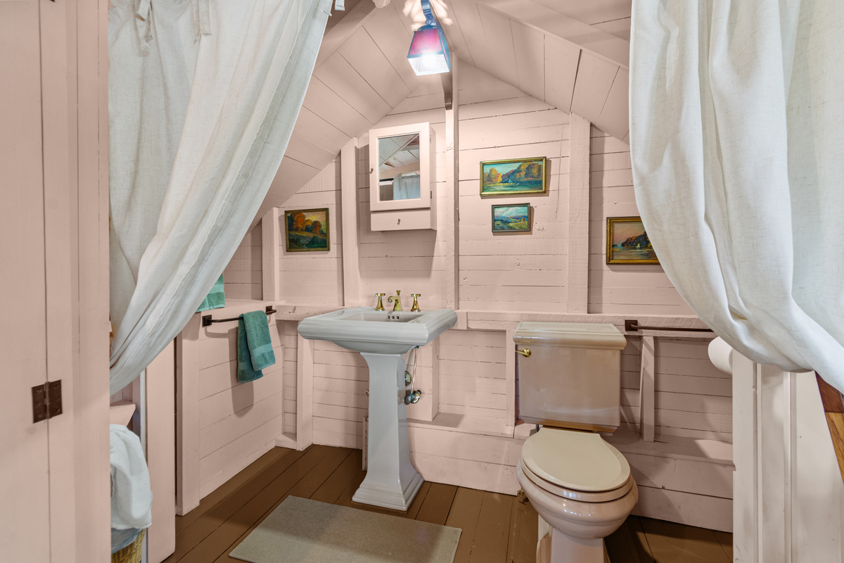 Designed with the home's rustic charm in mind, the upstairs half bath includes a sink and toilet with a privacy curtain instead of a traditional door.