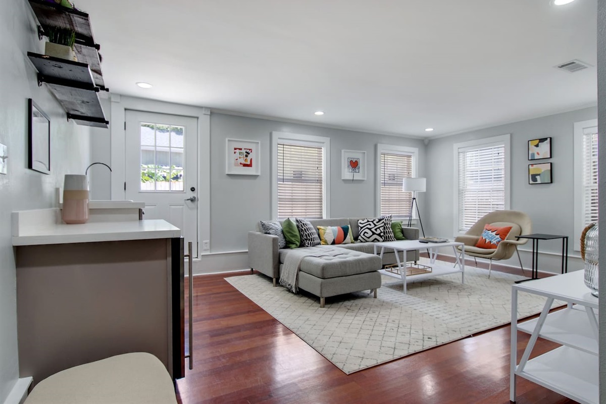 Living room with sectional sofa, wet bar, big screen smart tv, and rear courtyard access.