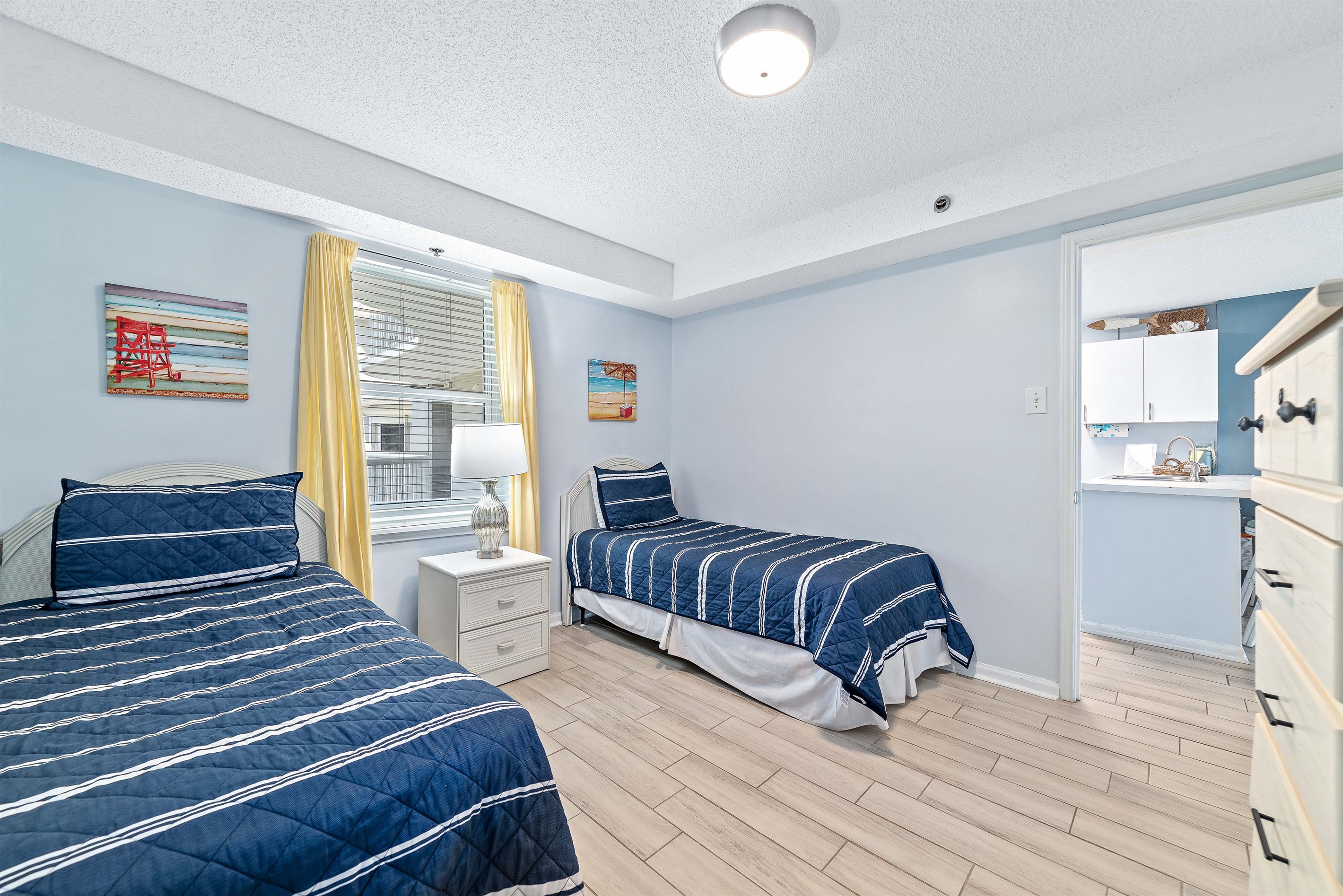 This well-appointed bedroom offers two cozy twin beds, soft lighting, and a window providing natural light and a pleasant outlook.