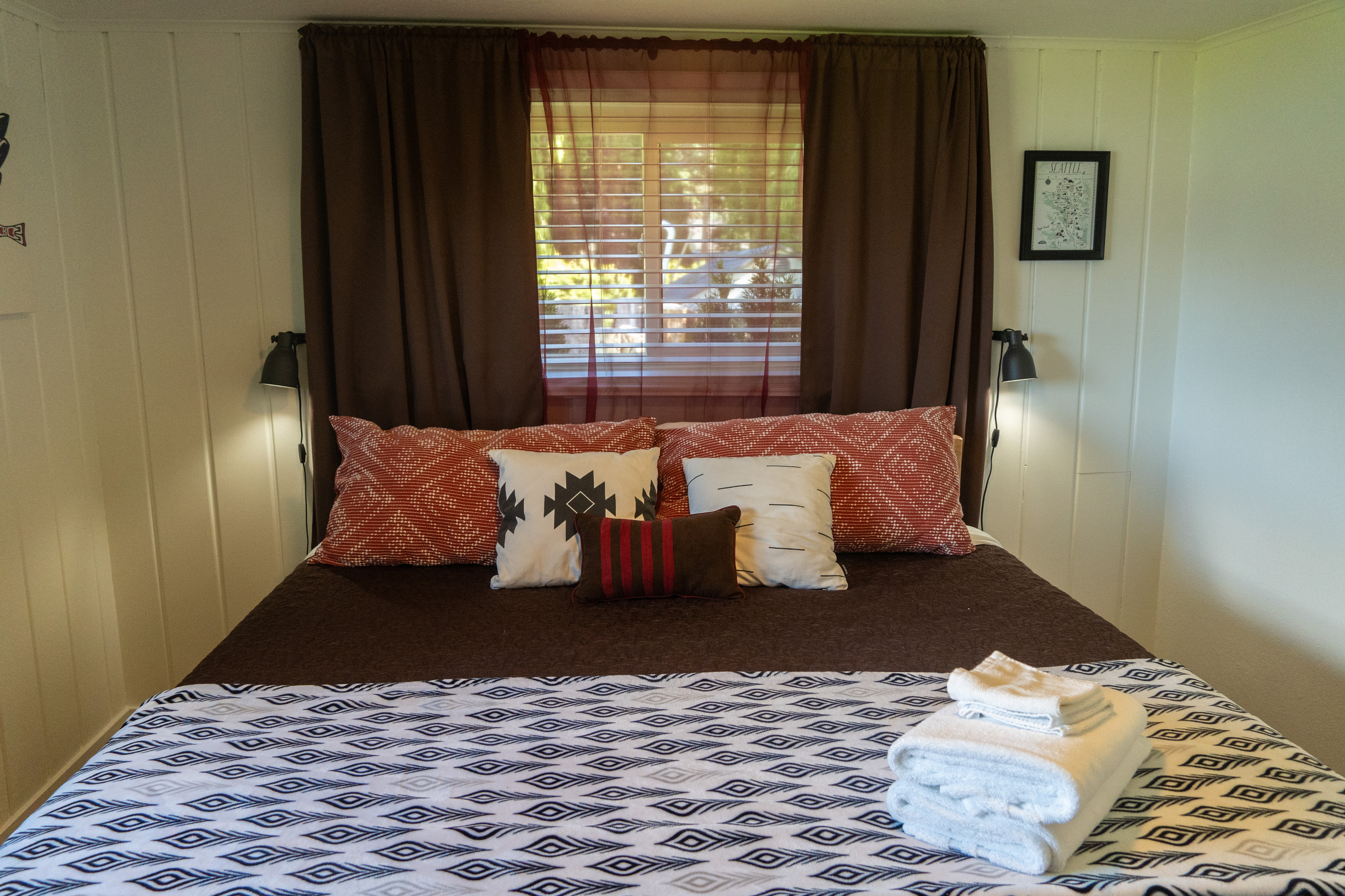 The master bedroom features a king bed with patterned textiles and layered textures throughout. Curtains, bedding, and rug create a warm, inviting, and thoughtfully styled retreat.