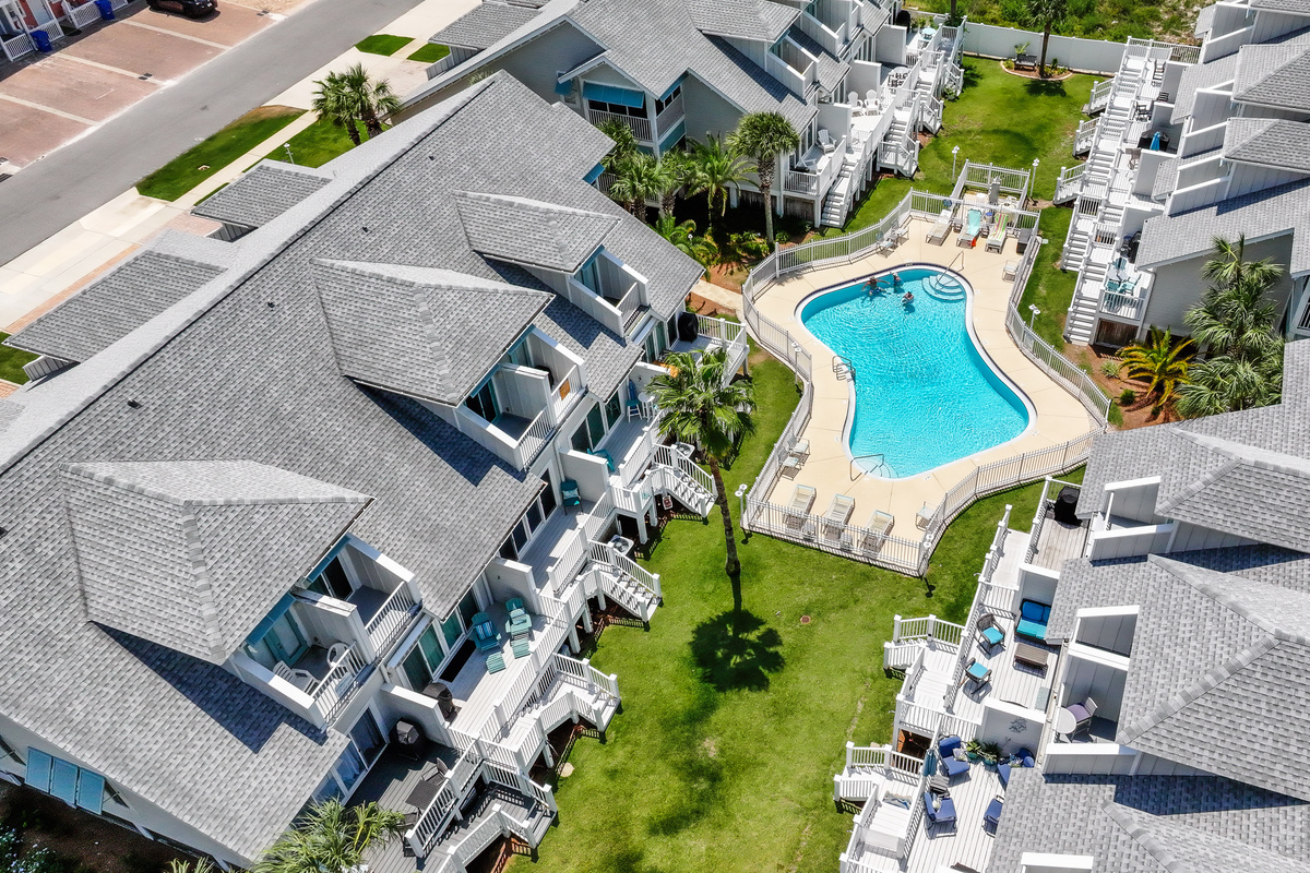 Beautiful aerial view showcasing the resort-style pool, landscaped grounds, and convenient location near the beach