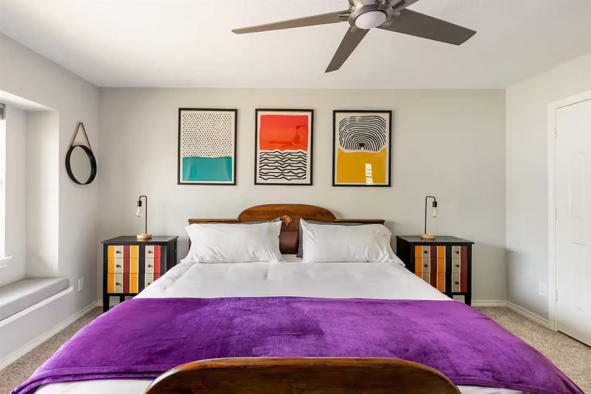 Spacious bedroom with king bed and vibrant wall art.