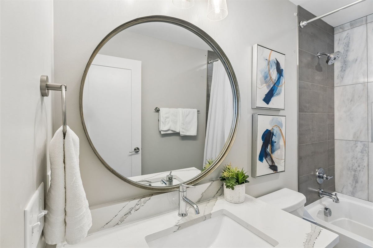 Step into the third full bathroom and you'll get the same clean finish as the rest of the house &mdash; tub-shower combo, white tile, ready for your group.