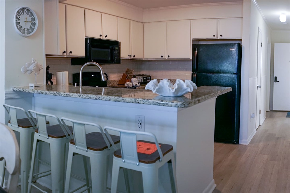 Bright welcoming kitchen with a clean, coastal feel. Breakfast bar with barstools for casual dining or to gather while cooking.