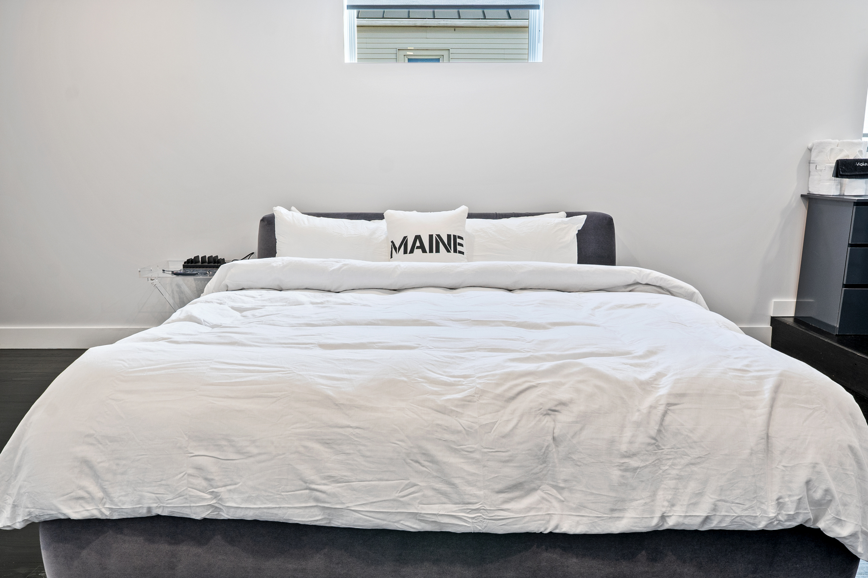 Sleep deeply in the primary suite. Features a King bed with crisp white linens, a plush upholstered frame, and remote-controlled automatic blackout blinds. A quiet sanctuary right in the heart of downtown Bar Harbor near Acadia National Park.