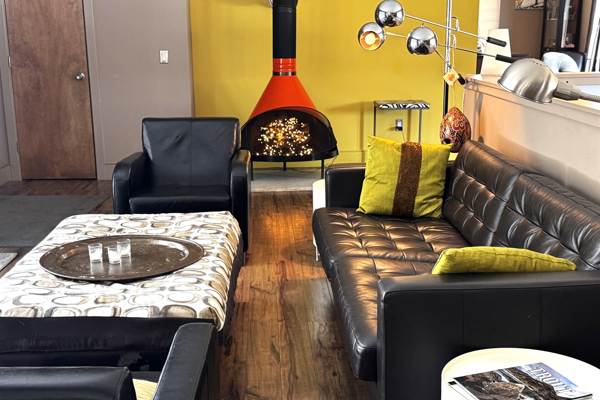 Modern mid-century lounge on the main level featuring a decorative vintage stove and designer seating. This bright social hub opens directly to the 33ft deck, offering a seamless indoor-outdoor connection to the Acadia National Park border.