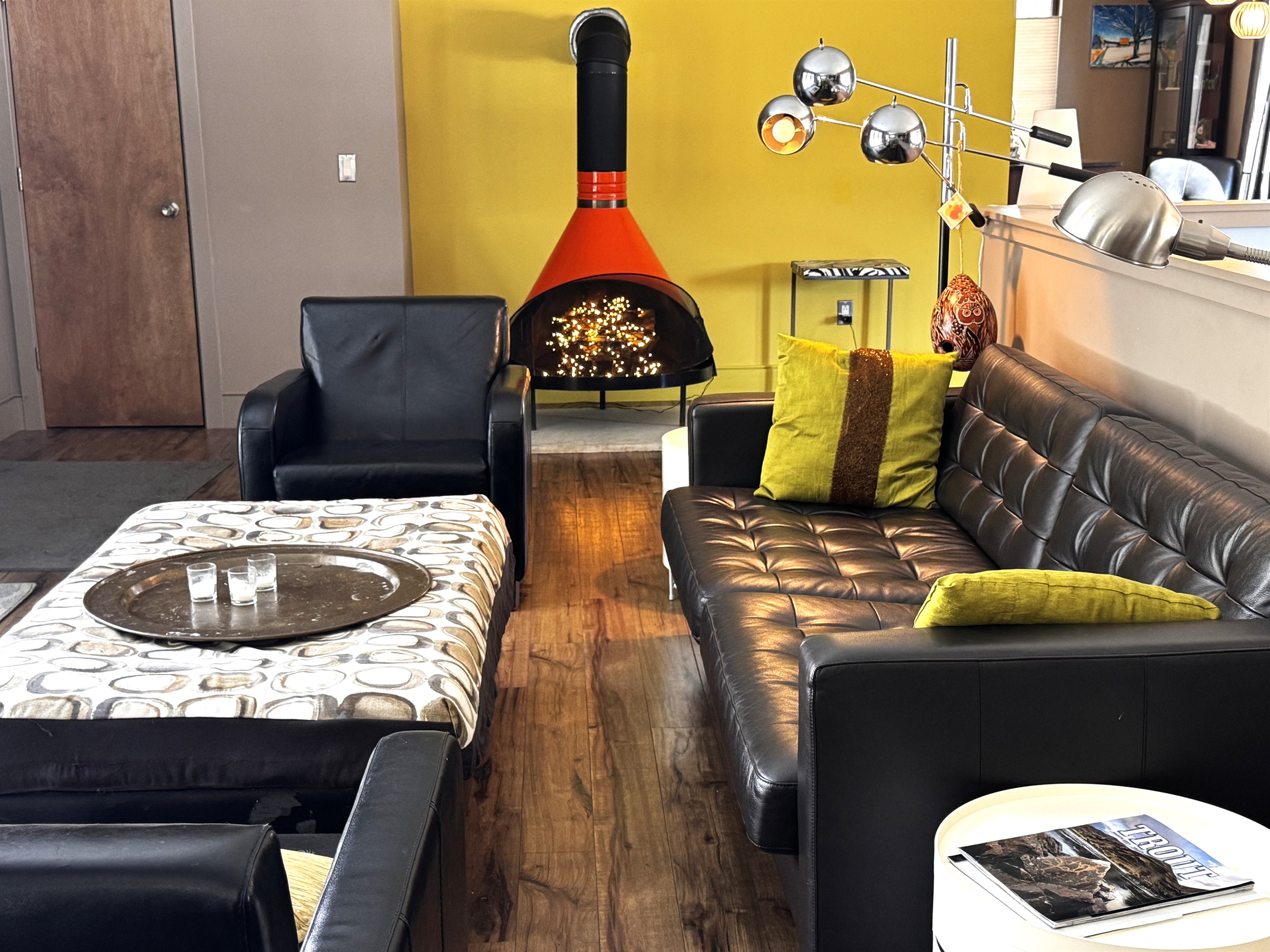 Modern mid-century lounge on the main level featuring a decorative vintage stove and designer seating. This bright social hub opens directly to the 33ft deck, offering a seamless indoor-outdoor connection to the Acadia National Park border.