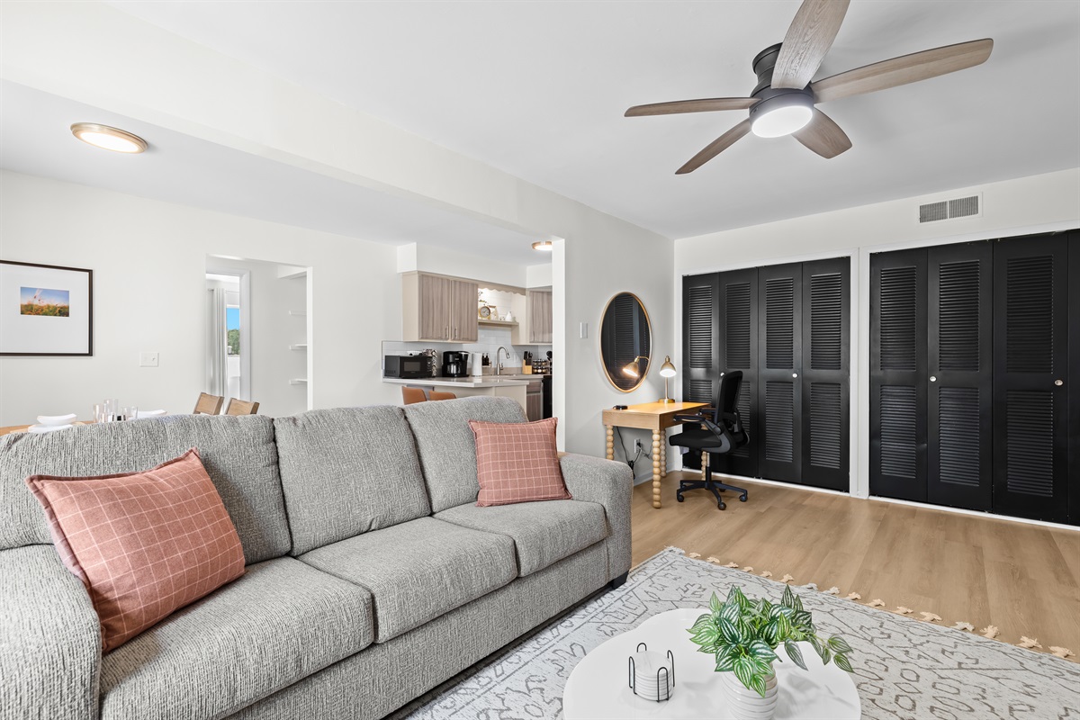 Open-concept living area with plush seating, work desk, and natural light.