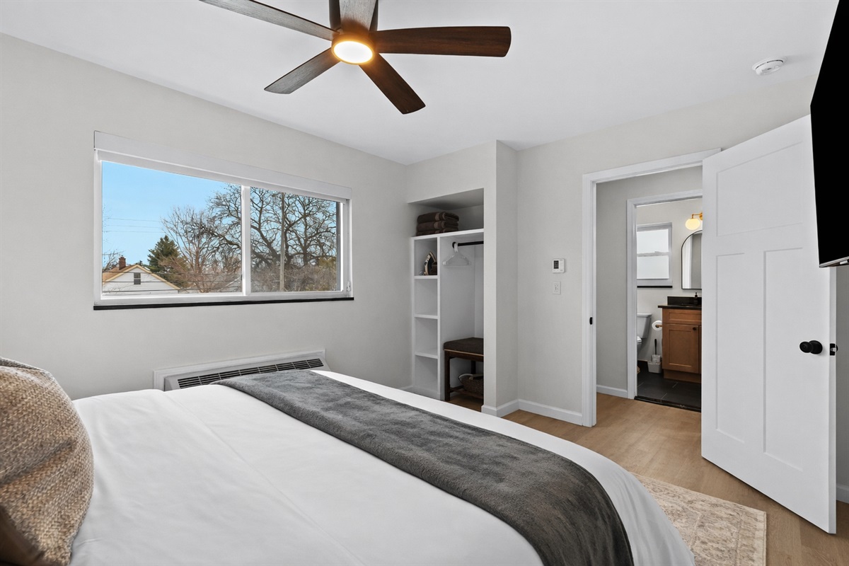 Spacious bedroom with a plush bed, ceiling fan, ample storage, and a private bath—bright, comfortable, and perfect for a relaxing stay.