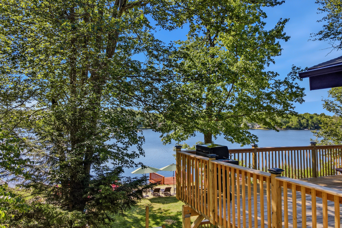 Deck rail view framed by mature trees with Lake Carobeth sparkling beyond