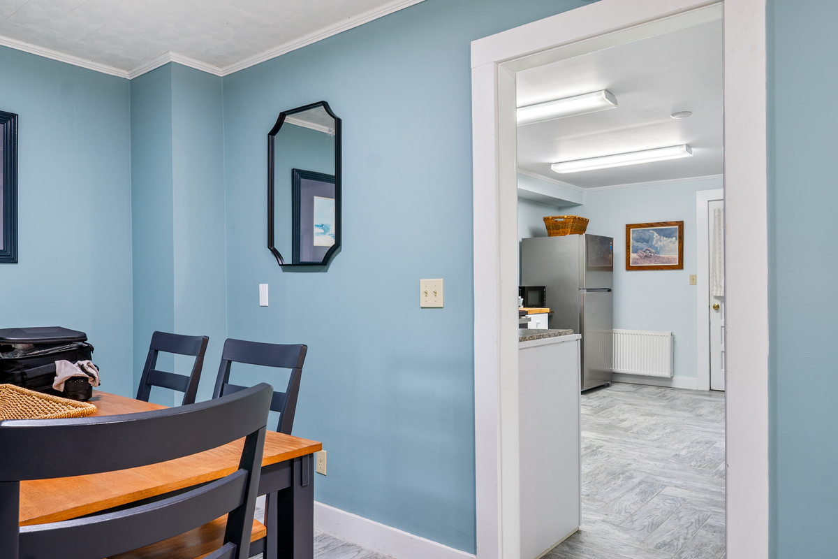 Stay connected with your group while prepping meals. This view from the dining room table looks right into the bright kitchen, showcasing a spacious, open flow that makes serving dinner and sharing stories from your Maine adventures a breeze.