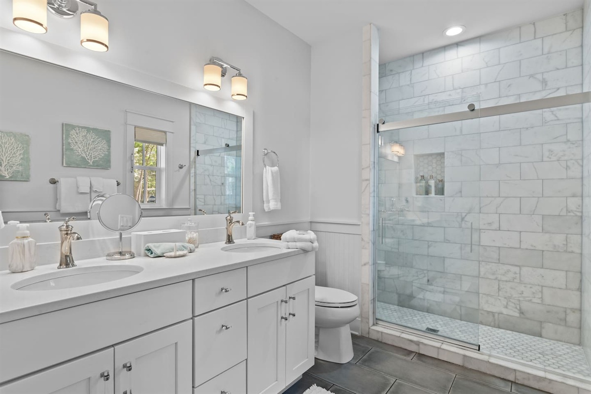First-floor king suite bathroom with double vanity and marble shower.