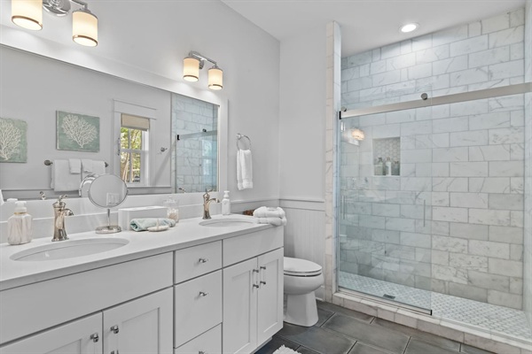 First-floor king suite bathroom with double vanity and marble shower.