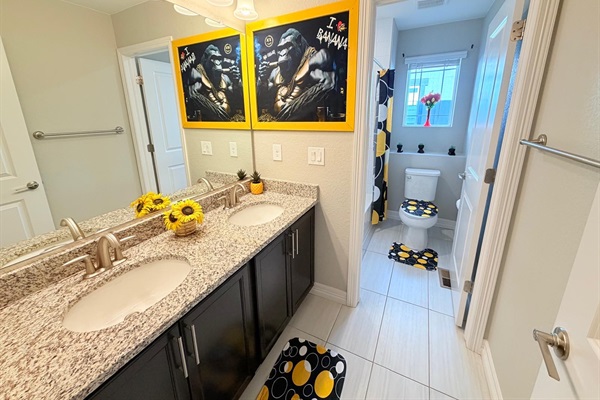 An additional full bathroom upstairs offers double sinks with storage cabinets, a toilet, and a tub & shower combination with a rain-style showerhead, making it easy for guests to get ready.