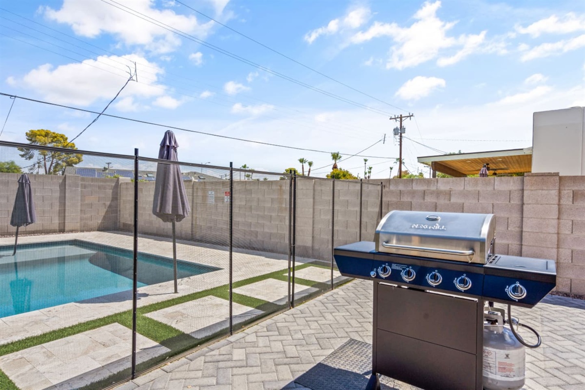 Private backyard pool with lounge chairs, grill, umbrella shade, fire pit seating, and a bright outdoor space 