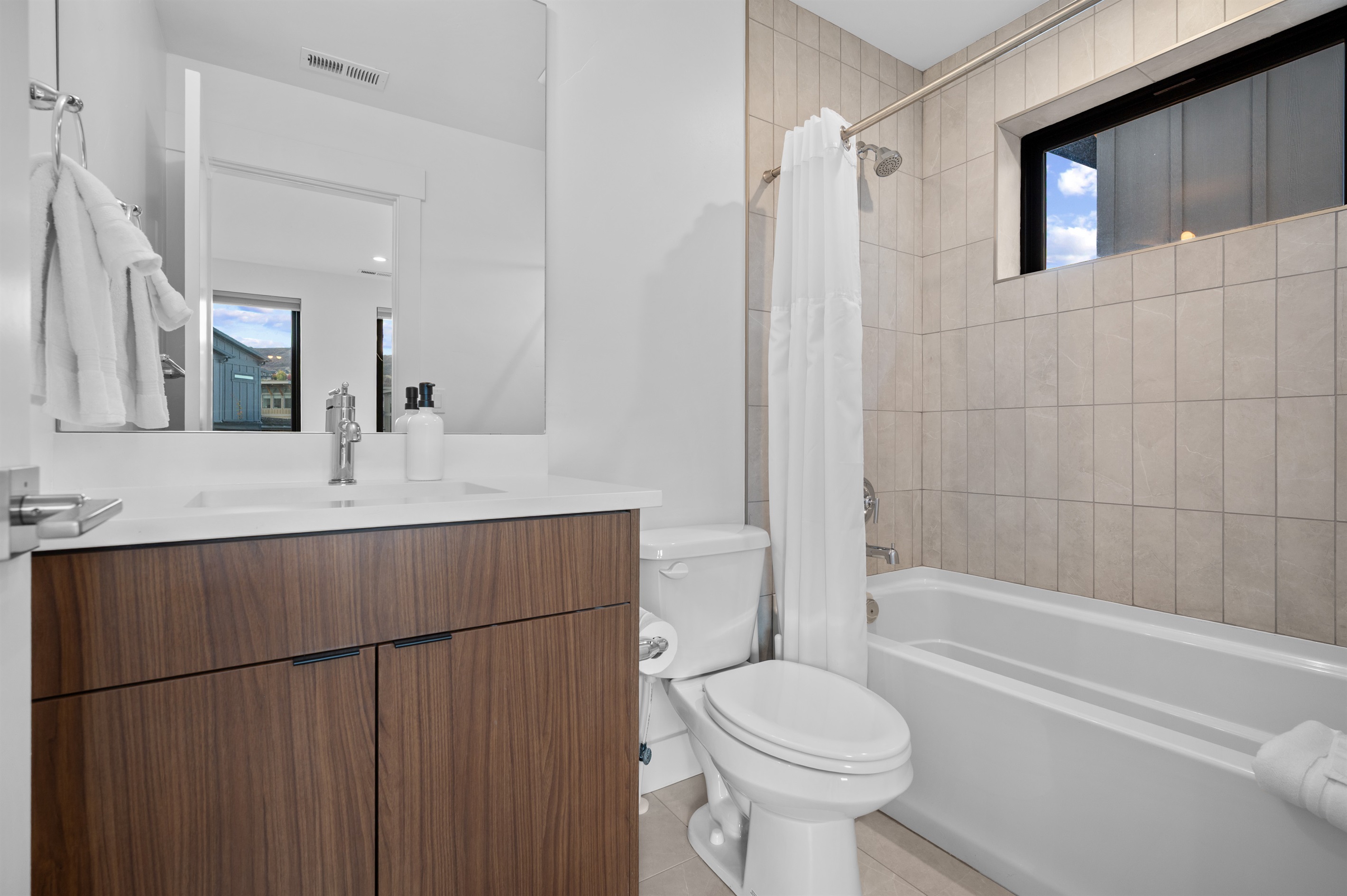 En-suite bathroom with tiled tub/shower combo and modern vanity.