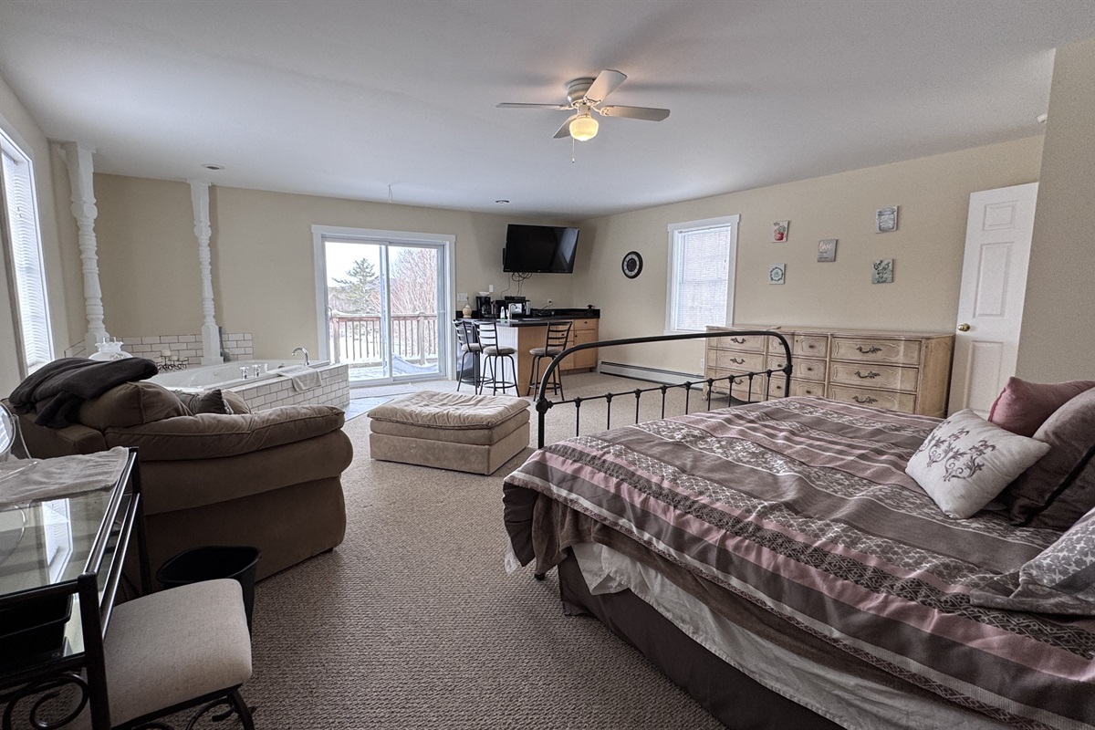 Primary bedroom with private wet bar, large stand-alone soaking tub, and access to private balcony 