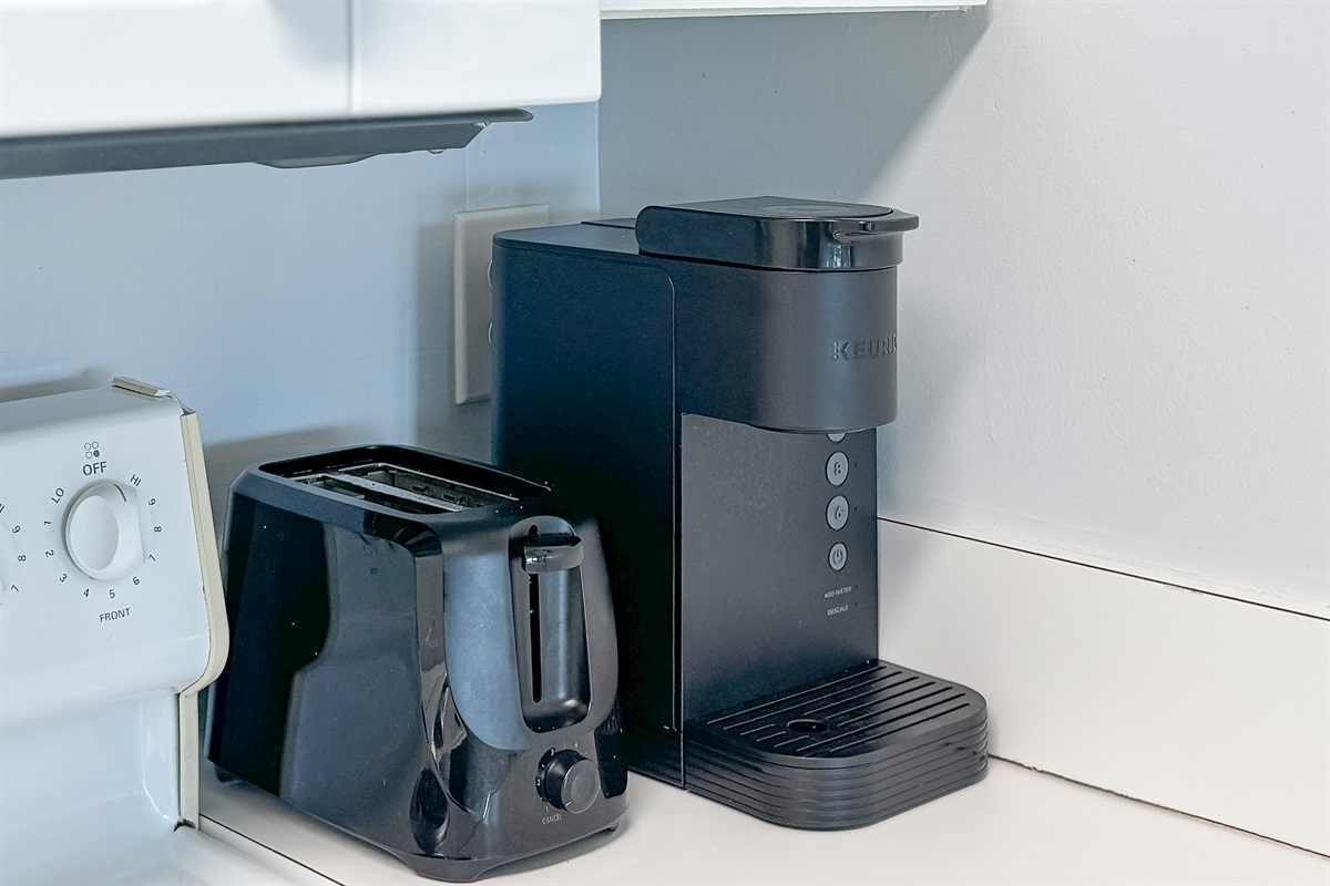 This kitchen features a dual coffee setup, offering both a classic coffee pot and a single-serve machine, alongside a toaster and utensil holder, ensuring you have everything you need for a comfortable stay.