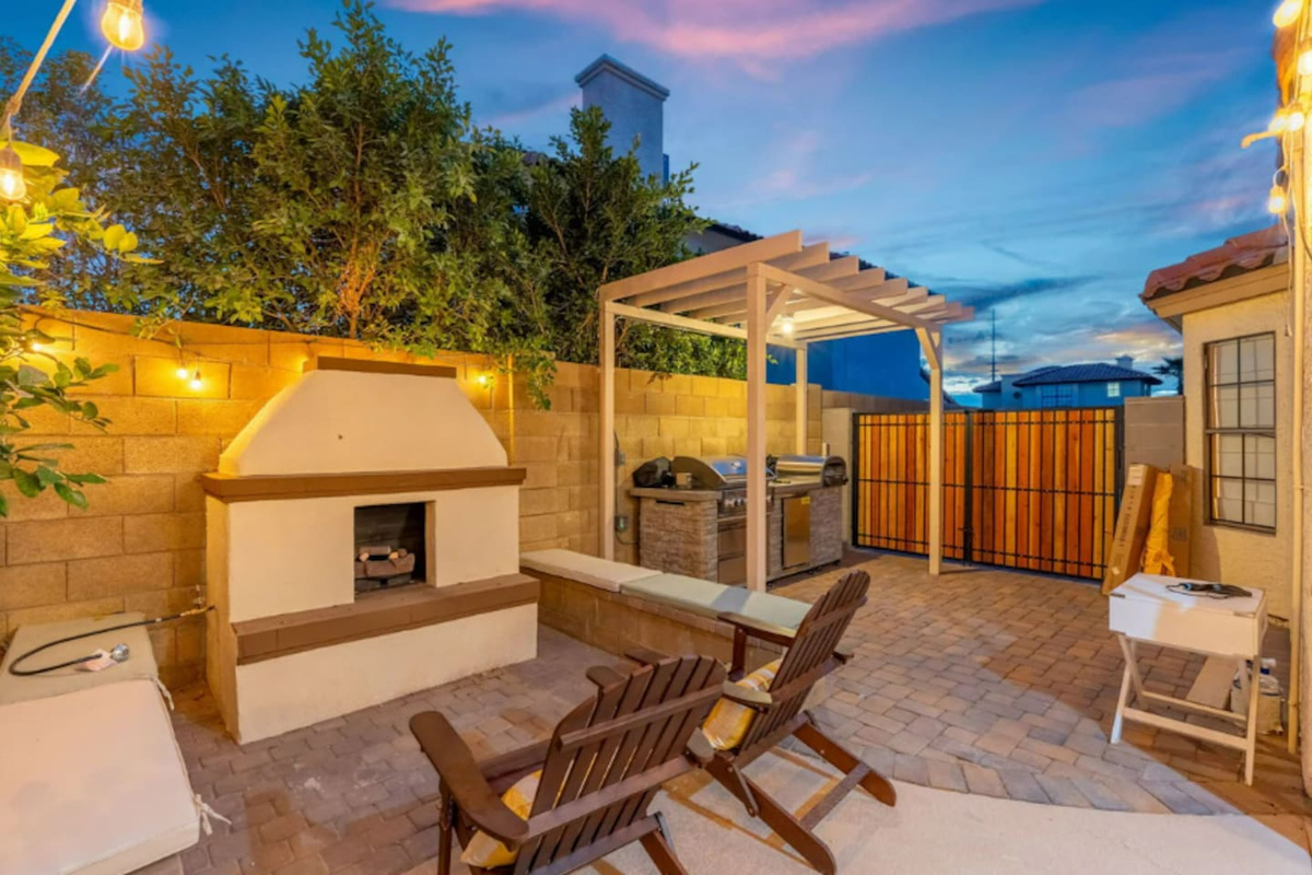 Twilight backyard with fireplace, pergola, grill, and lounge chairs—perfect for evening gatherings under the stars.