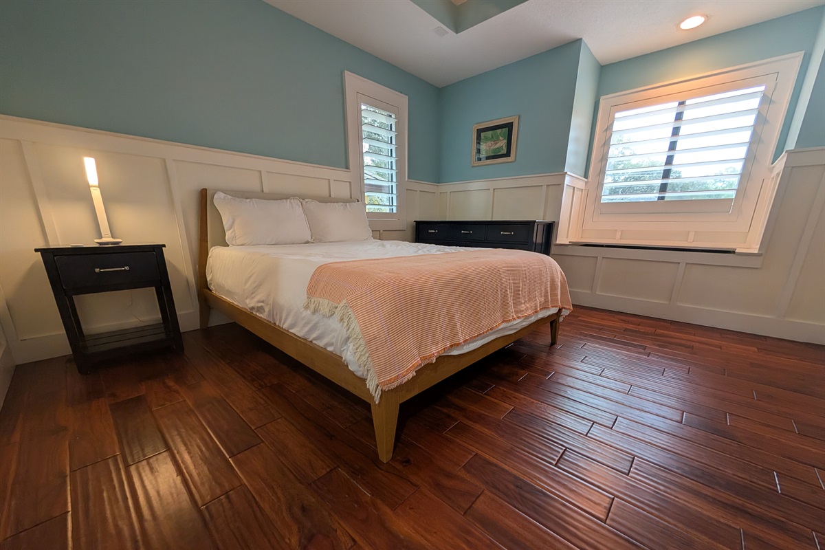 Well lit upstairs guest bedroom with a queen bed