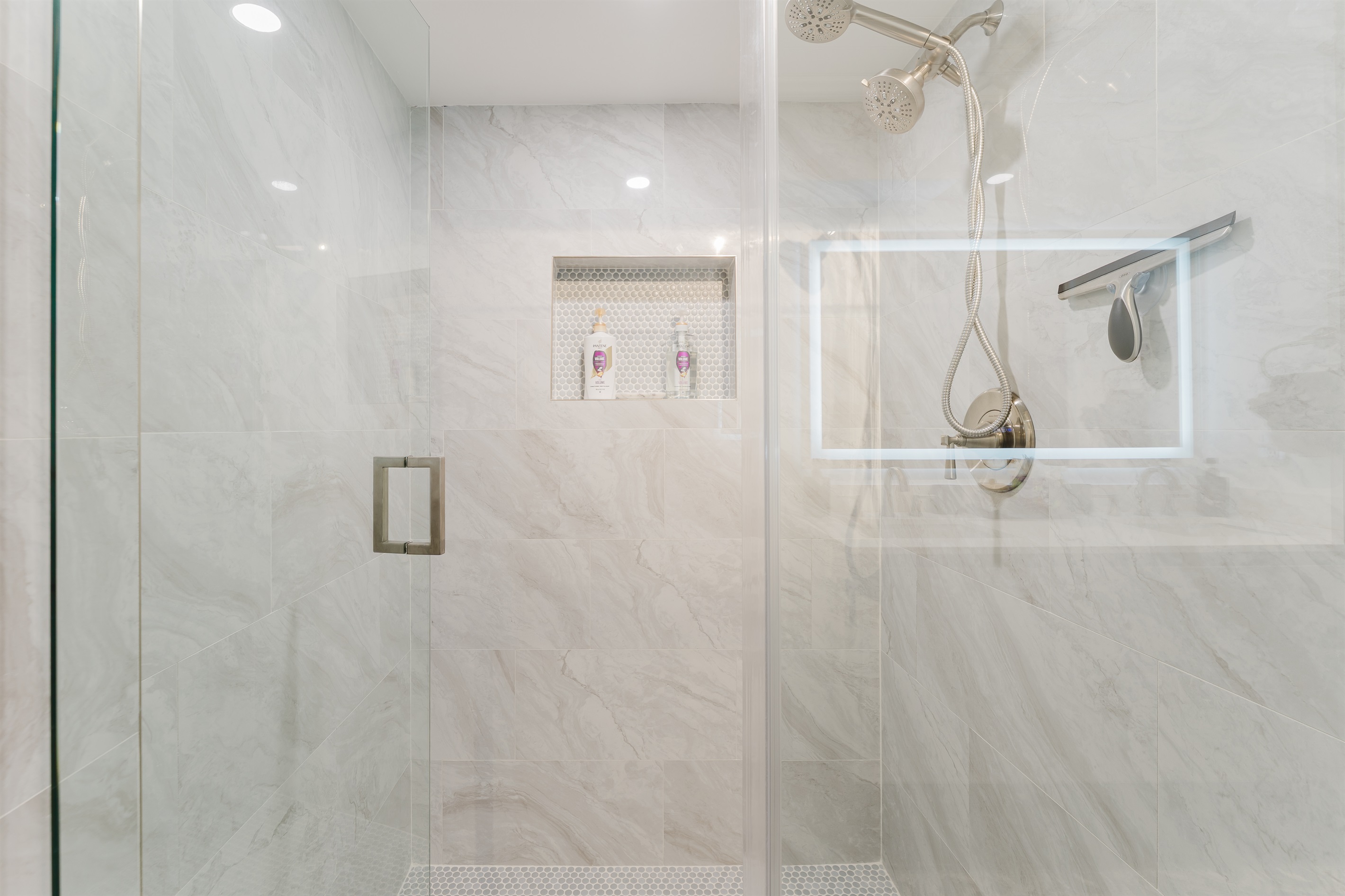 Spacious primary bathroom with double vanity, LED-lit mirror, and modern walk-in glass shower
