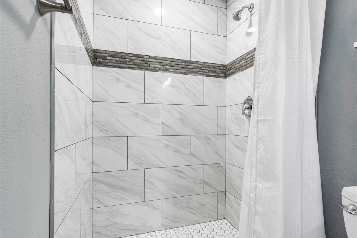 From the hexagon-tiled shower floor to the granite countertop and sleek faucet, every detail is thoughtfully curated.