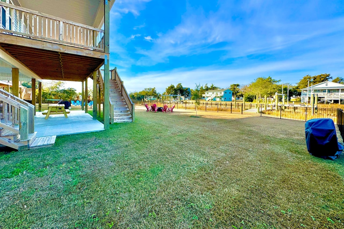 Private backyard dock with boat lift and fillet table, fenced-in backyard, fire pit with Adirondack chairs, hammocks, propane grill, picnic table, outdoor shower, expansive waterfront back deck with table and seating, neighborhood boat ramp and dock