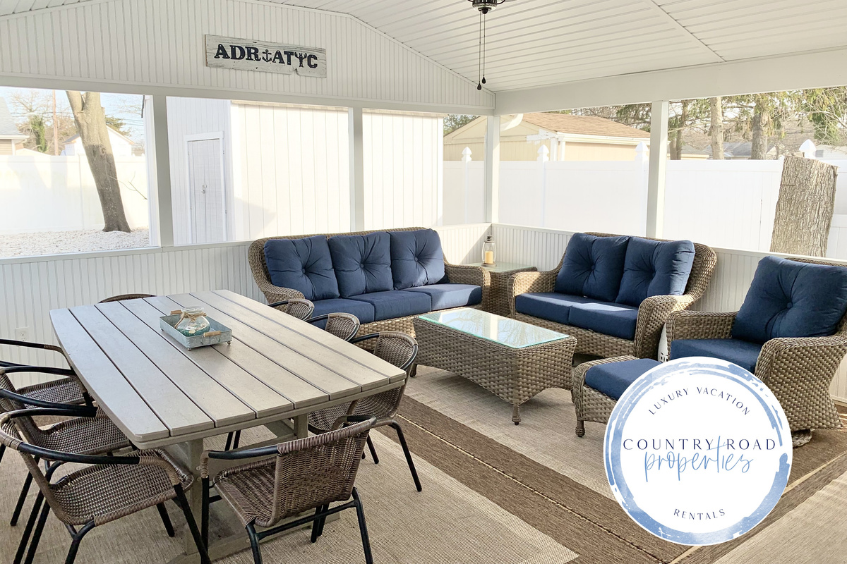 Experience the best of indoor-outdoor living in our screened-in sunroom. Kick back on navy wicker seating to watch the game or enjoy a meal at the large dining table—all while staying protected from the elements in a bright, coastal setting.